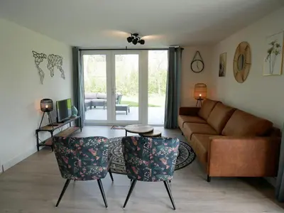 a living room with a couch and a table and chairs at Vakantiehuis met sauna op Recreatiepark de Wielen - 64 in Sint Maarten