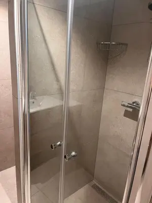 a shower with a glass door next to a sink at Beachhouse Noteboom, omheinde tuin in Noordwijk aan Zee