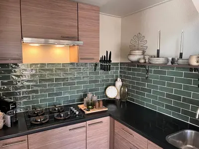 a kitchen with green tile on the wall at Beachhouse Noteboom, omheinde tuin in Noordwijk aan Zee