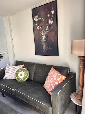 a couch in a living room with a picture of a deer at Beachhouse Noteboom, omheinde tuin in Noordwijk aan Zee