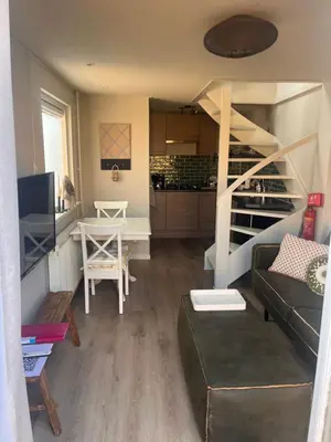 a small living room with a couch and a staircase at Beachhouse Noteboom, omheinde tuin in Noordwijk aan Zee