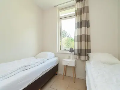 two beds in a room with a window at Bungalow in South Holland near the Beach in Noordwijk