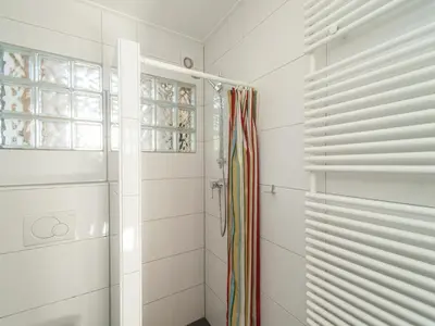 a white bathroom with a shower and a window at Bungalow in South Holland near the Beach in Noordwijk