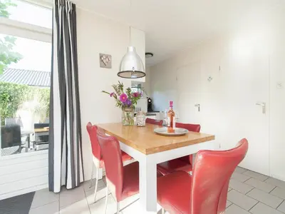 a kitchen with a wooden table and red chairs at Bungalow in South Holland near the Beach in Noordwijk