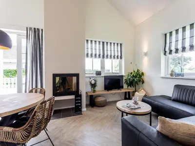 a living room with a couch and a table at Bungalow near Dutch Coast & Forest in Noordwijk