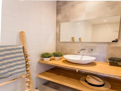 a bathroom with a sink and a mirror and towels at Bungalow near Dutch Coast & Forest in Noordwijk