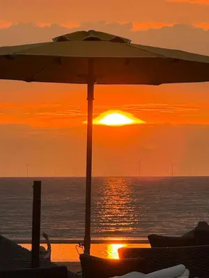 an umbrella on a beach with the sun setting at Walhalla in Zandvoort