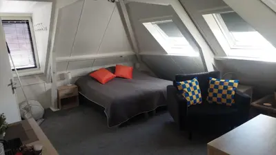 a bedroom with a bed with two pillows and a chair at Walhalla in Zandvoort