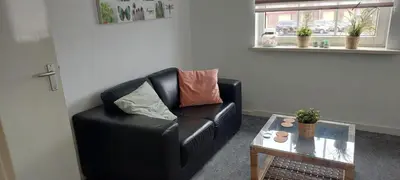 a black leather couch in a living room with a table at Walhalla in Zandvoort