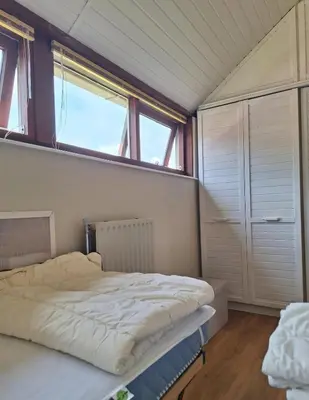 a bed in a room with a large window at Rekerlanden 86 in Warmenhuizen