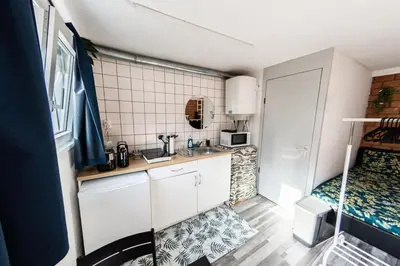 a small kitchen with a sink and a bed at Tiny House Zaandam, Tranquility and easy Connection in Zaandam