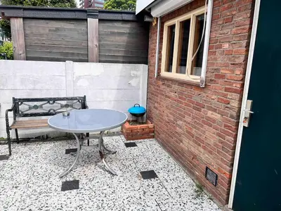 a patio with a table and a bench next to a brick wall at Tiny House Zaandam, Tranquility and easy Connection in Zaandam