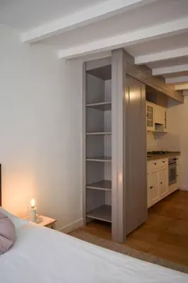 a bedroom with a white bed and a kitchen at NEW cosy apartment in 9 streets in Amsterdam