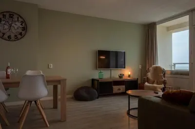 a living room with a television and a table and chair at Strand166 in Egmond aan Zee