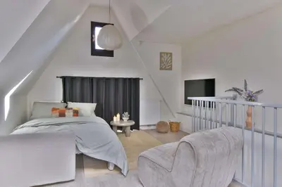 a white bedroom with a bed and a chair at City apartment Alkmaar in Alkmaar