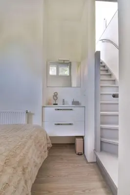 a bedroom with a bed and a sink and stairs at City apartment Alkmaar in Alkmaar