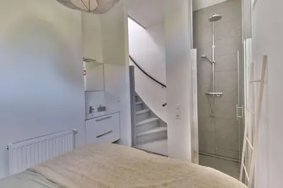 a white bedroom with a staircase and a shower at City apartment Alkmaar in Alkmaar