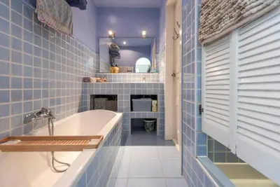 a blue tiled bathroom with a tub and a sink at Beachhouse36 in Zandvoort