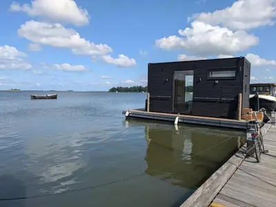 a black house on a dock on a body of water at Modern Stay Tiny Houseboat to visit Amsterdam in Monnickendam