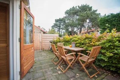 a wooden table and chairs on a patio at Therese with free parking in Zandvoort