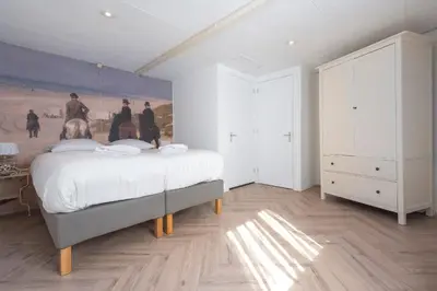 a bedroom with a bed with a painting on the wall at Therese with free parking in Zandvoort