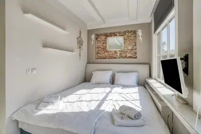 a white bedroom with a bed and a tv at Authentic apartment in Alkmaar in Alkmaar