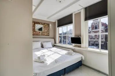 a bedroom with a bed and a tv and windows at Authentic apartment in Alkmaar in Alkmaar