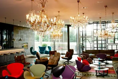 a lobby with chandeliers and chairs and tables at Motel One Amsterdam in Amsterdam