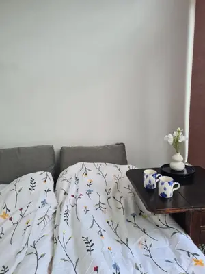 a bed with a comforter and a table with mugs on it at Tiny Garden Room - in city center in Alkmaar
