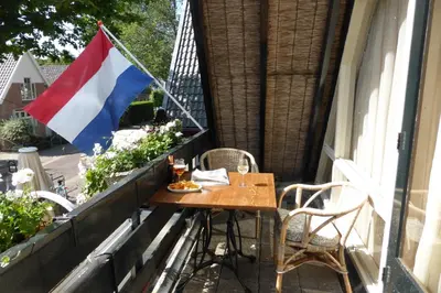 a flag on a balcony with a table and chairs at Duinberk B&B hotel en Brasserie in Schoorl