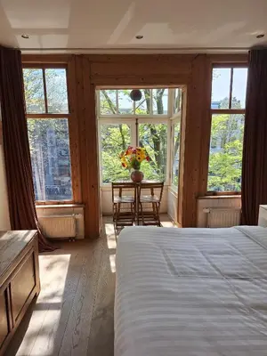 a bedroom with a bed and a table and windows at A B&B Amsterdam in Amsterdam