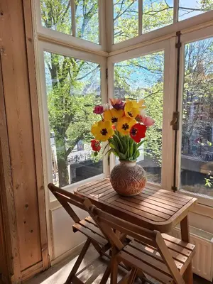 a vase of flowers sitting on a table in front of a window at A B&B Amsterdam in Amsterdam