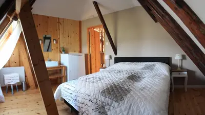 a bedroom with a bed in a room with wooden floors at Bed & Breakfast De Stolp in Zuidoostbeemster