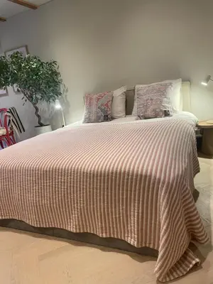a bedroom with a large bed with a striped blanket at B&B Goldie in Aerdenhout
