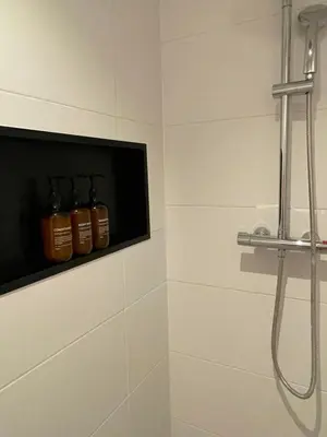 a bathroom with three bottles of alcohol on a shelf at B&B Goldie in Aerdenhout