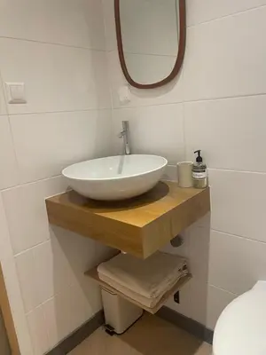 a bathroom with a white bowl sink on a wooden shelf at B&B Goldie in Aerdenhout