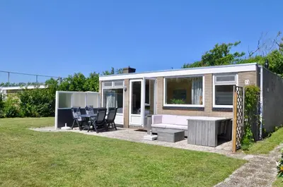 a tiny house with a table and chairs in a yard at Garnekuul 34 in Ons Belang