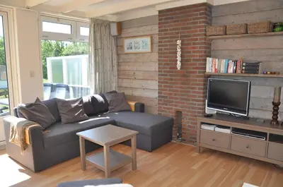 a living room with a couch and a tv at Garnekuul 34 in Ons Belang
