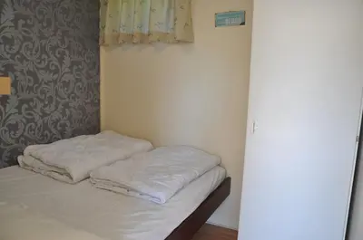 a unmade bed in a room with a curtain at Garnekuul 34 in Ons Belang
