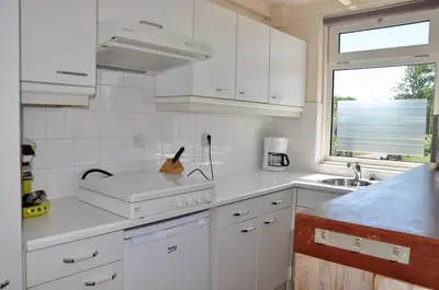 a kitchen with white cabinets and a sink and a window at Garnekuul 34 in Ons Belang