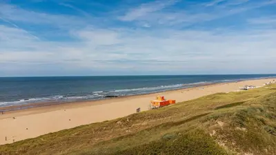 a beach with an orange building on the sand at Garnekuul 34 in Ons Belang