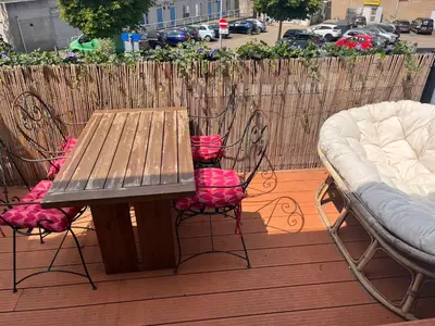 a wooden table and chairs on a deck with a bed at Appartement Huis ter Duinstraat in Noordwijk aan Zee