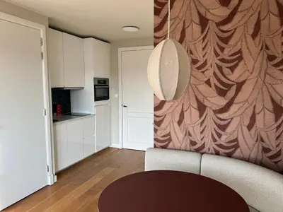 a living room with a table and a wall at Appartement Huis ter Duinstraat in Noordwijk aan Zee