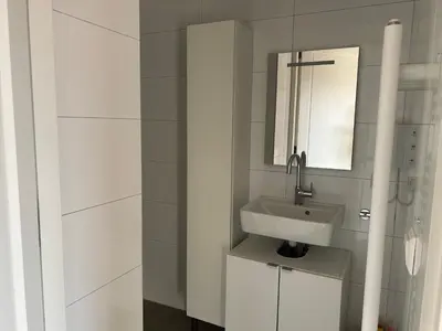 a white bathroom with a sink and a mirror at Appartement Huis ter Duinstraat in Noordwijk aan Zee