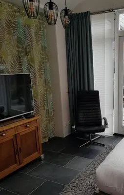 a living room with a tv and a chair at B&B Purmavida in Purmerend