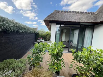 a house with a patio and a fence at Duinpoort Appartement in Castricum