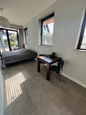 a bedroom with a bed and a desk and a table at Duinpoort Appartement in Castricum