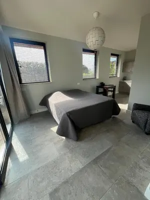 a bedroom with a bed and a pendant light at Duinpoort Appartement in Castricum