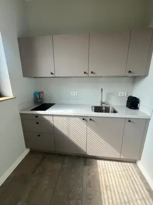 a kitchen with white cabinets and a sink at Duinpoort Appartement in Castricum