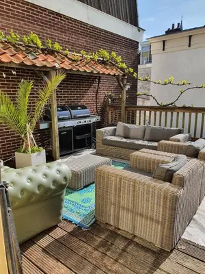 a patio with a grill and couches on a deck at Fantastic house with a large roof terrace downtown in Alkmaar